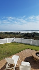A white picket fence in a yard with trees and grass.
