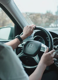 a man driving a car with his hands on the steering wheel