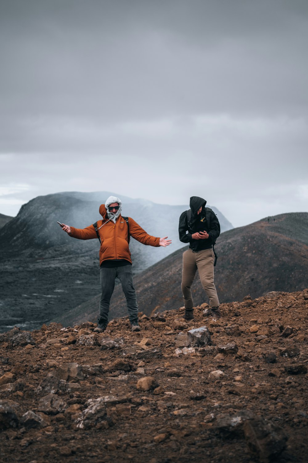 a couple of men standing on top of a mountain
