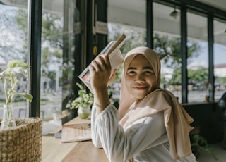 a woman in a hijab is holding a book