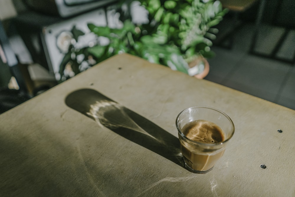 a glass of liquid sitting on top of a wooden table