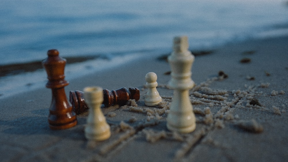 a group of chess pieces sitting on top of a sandy beach