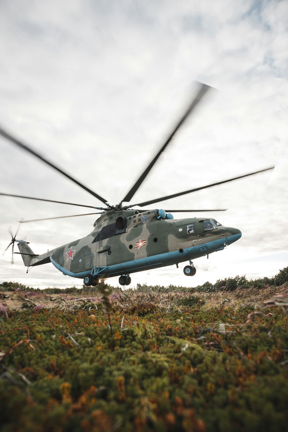 a military helicopter is flying low to the ground