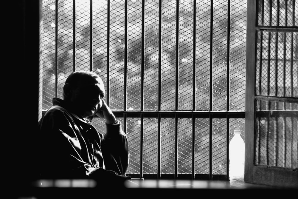 a man sitting in front of a window next to a jail cell