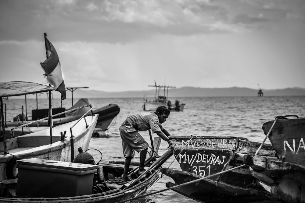 a black and white photo of a man on a boat