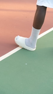 a person standing on a tennis court holding a tennis racquet