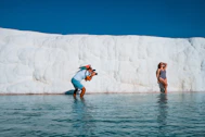 a woman taking a picture of a man in a body of water