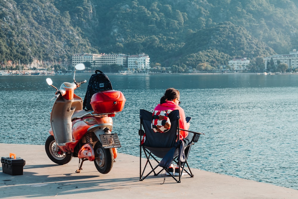 a woman sitting in a chair next to a motor scooter