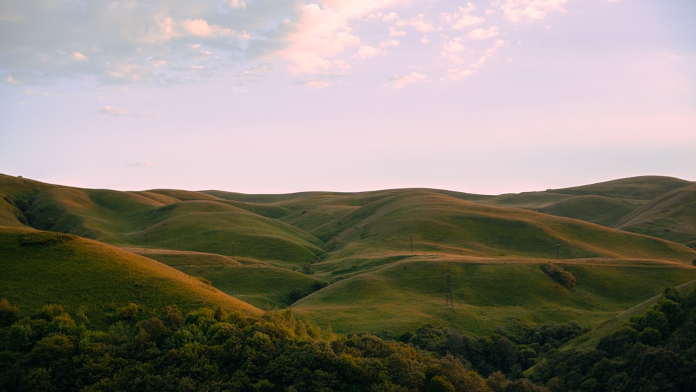 a hill covered in green hills under a cloudy sky