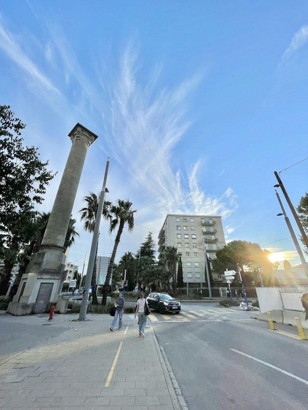 a couple of people walking down a street next to tall buildings