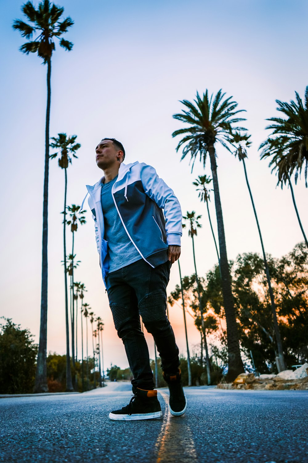 a man riding a skateboard down a street next to palm trees