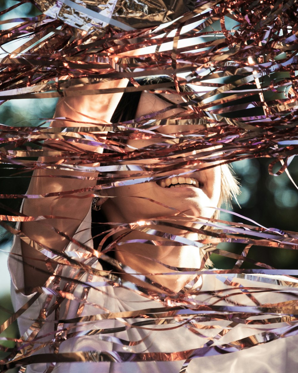 a woman is covering her face behind a bunch of tinsel