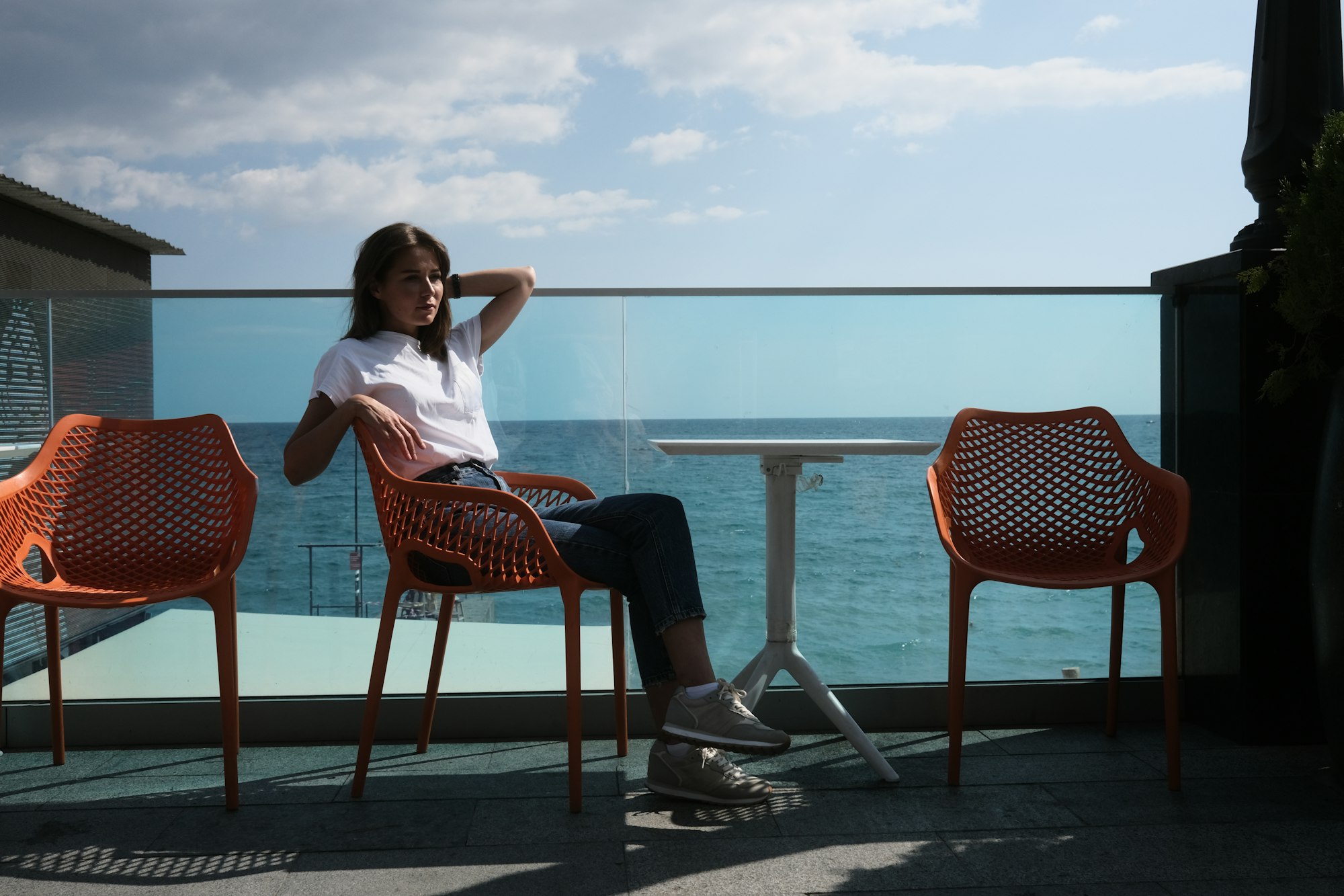 a woman sitting in a chair on a balcony overlooking the ocean