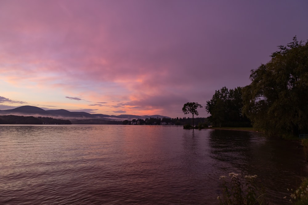 a beautiful sunset over a lake with mountains in the background