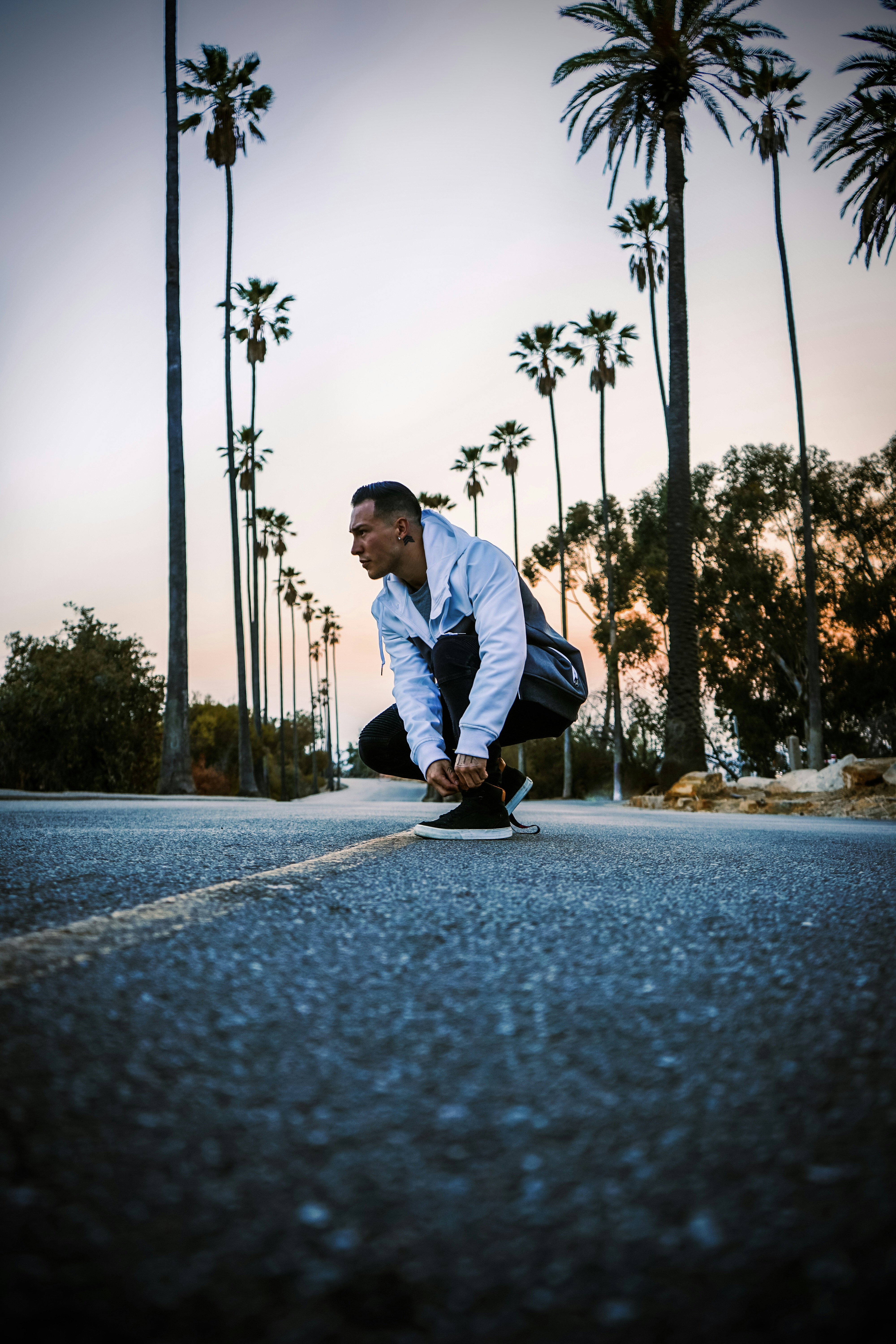 a man riding a skateboard down a street next to palm trees