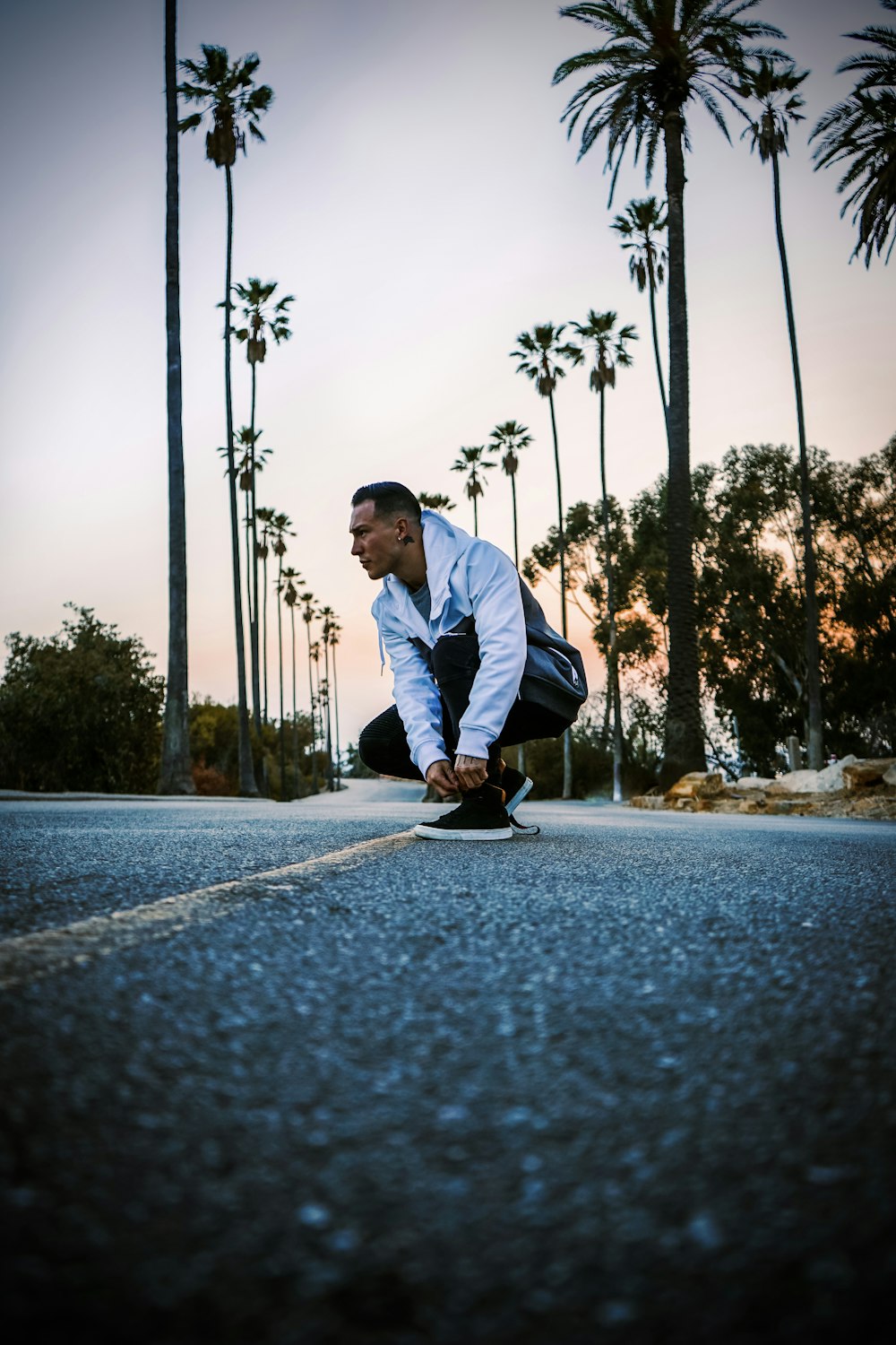 a man riding a skateboard down a street next to palm trees