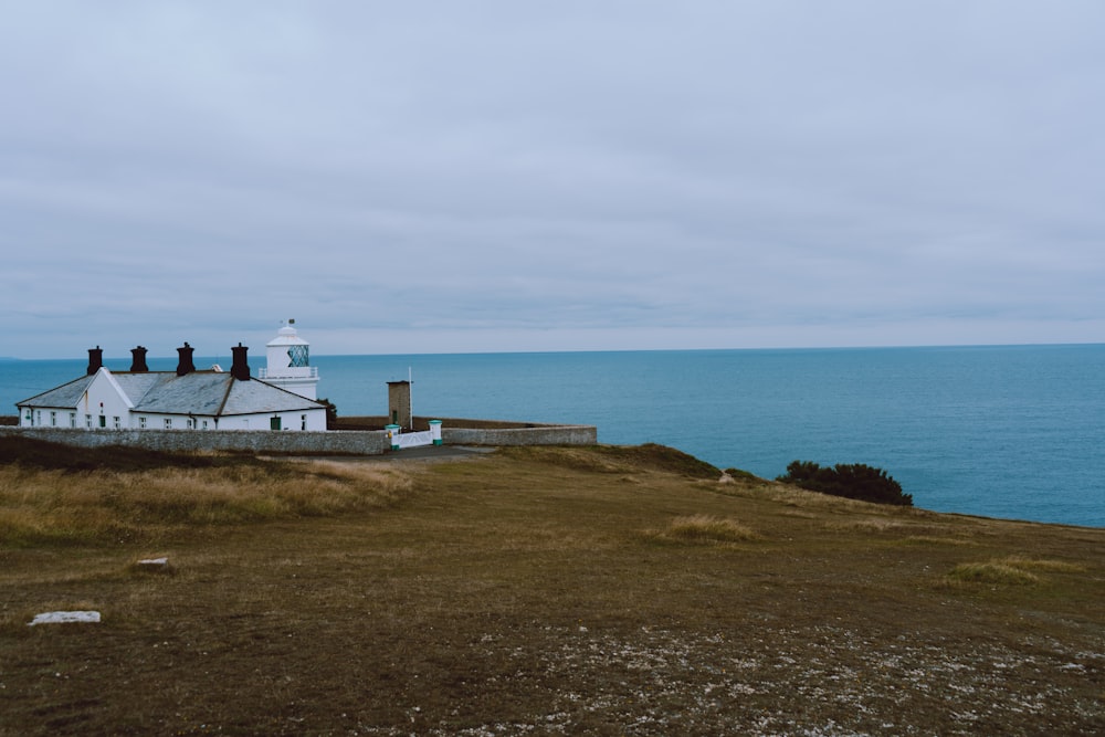 a white house sitting on top of a hill next to the ocean