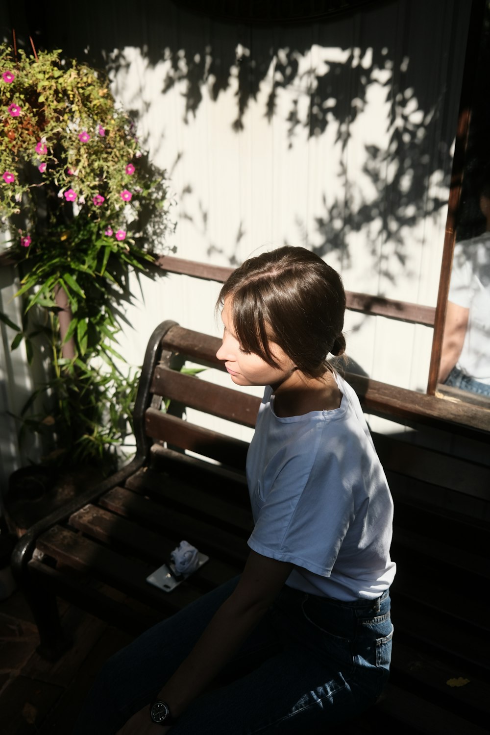 a woman sitting on a bench next to a potted plant