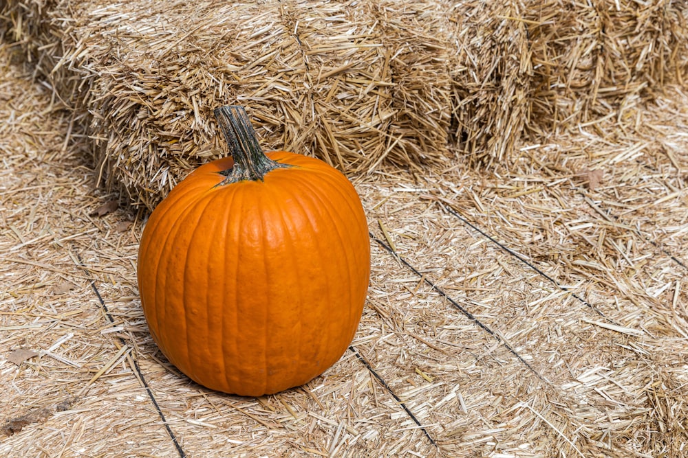a pumpkin sitting on top of a pile of hay