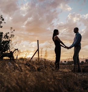 a man and a woman holding hands in a field