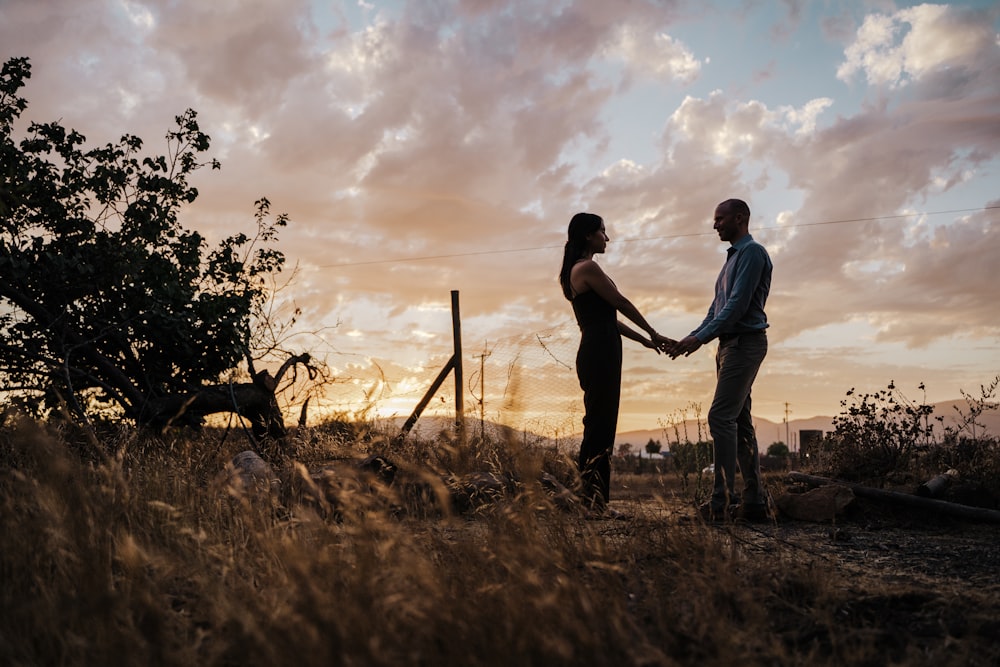 a man and a woman holding hands in a field