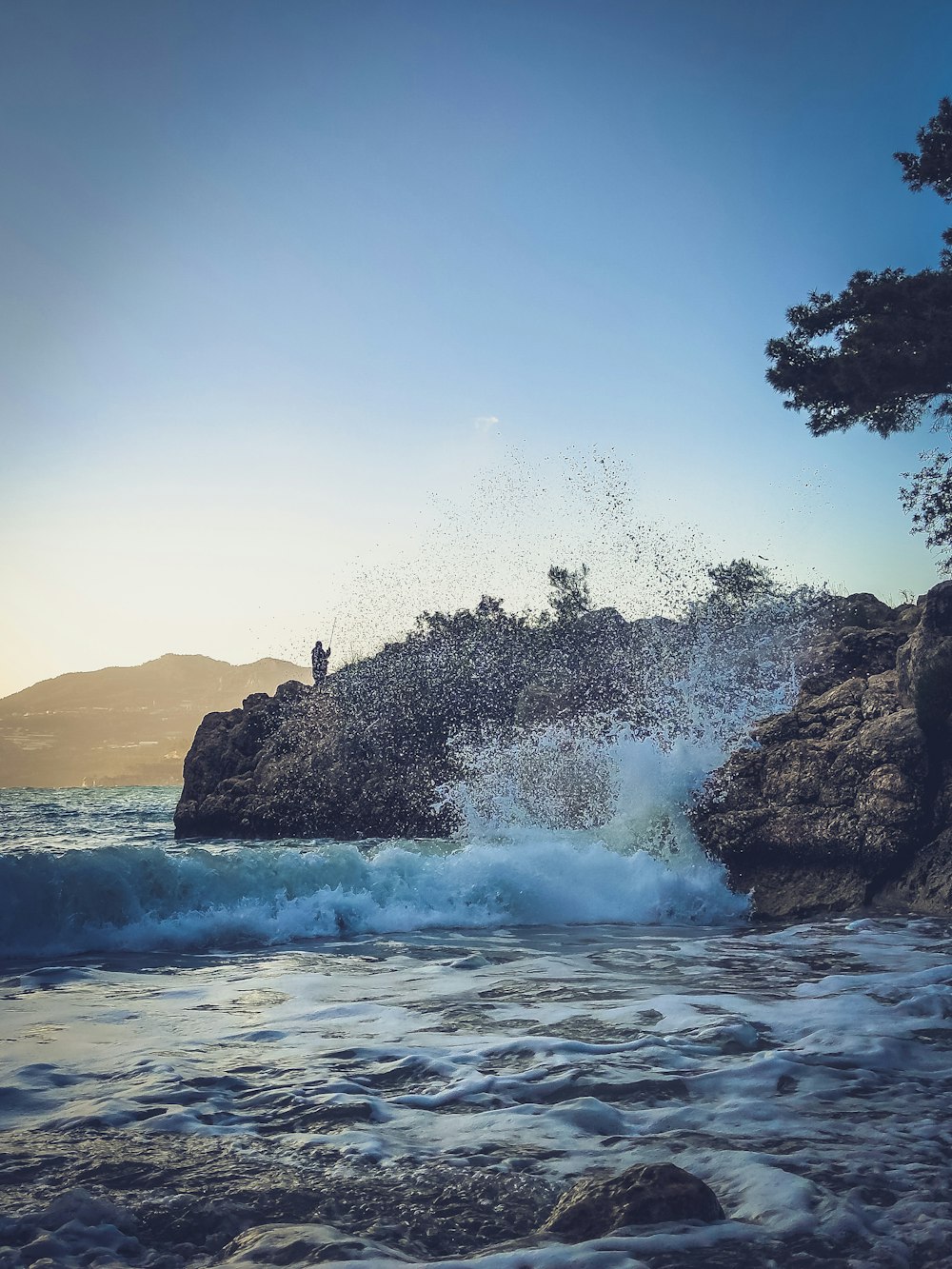 a person standing on top of a rock near the ocean