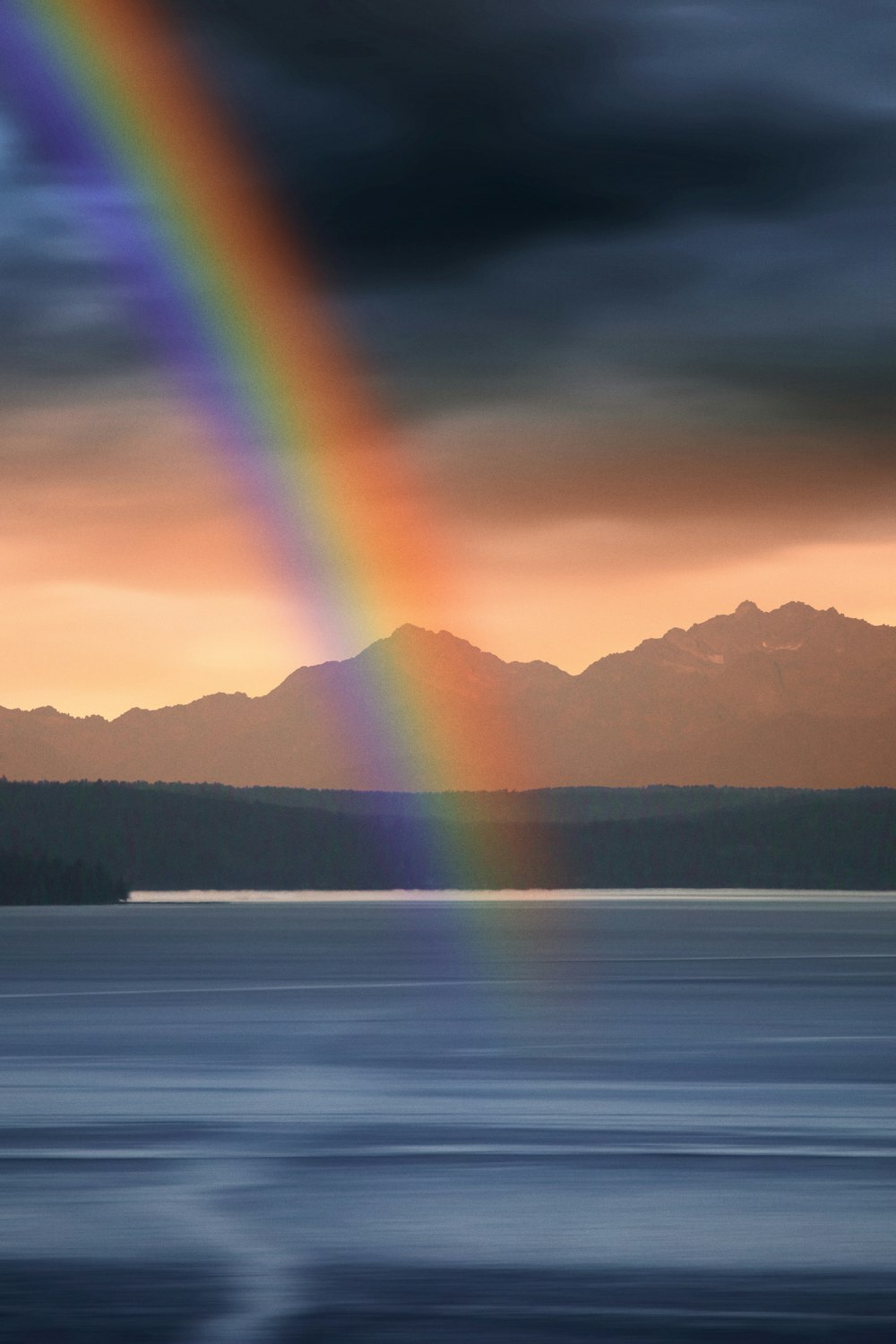 a rainbow shines in the sky over a body of water