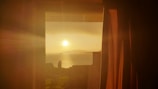 A serene sunset view from a window with curtains.