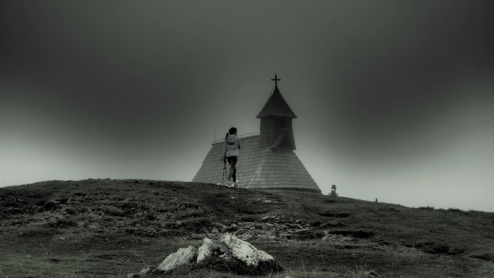 a black and white photo of a person standing on a hill