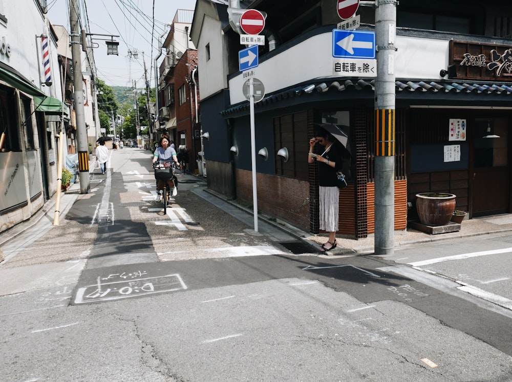 a man riding a bike down a street next to a tall building