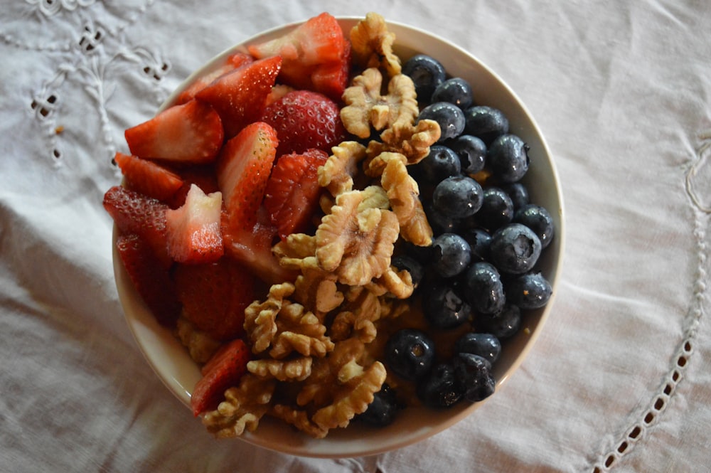 a bowl of cereal, berries, walnuts, and blueberries