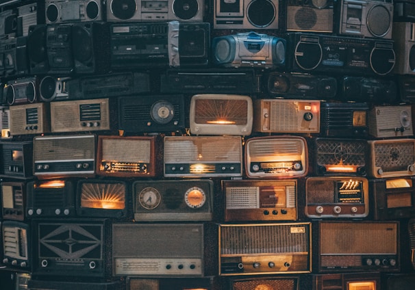 a large amount of old radio's stacked on top of each other