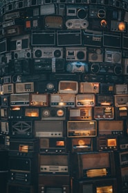a large amount of old radio's stacked on top of each other