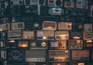 a large amount of old radio's stacked on top of each other