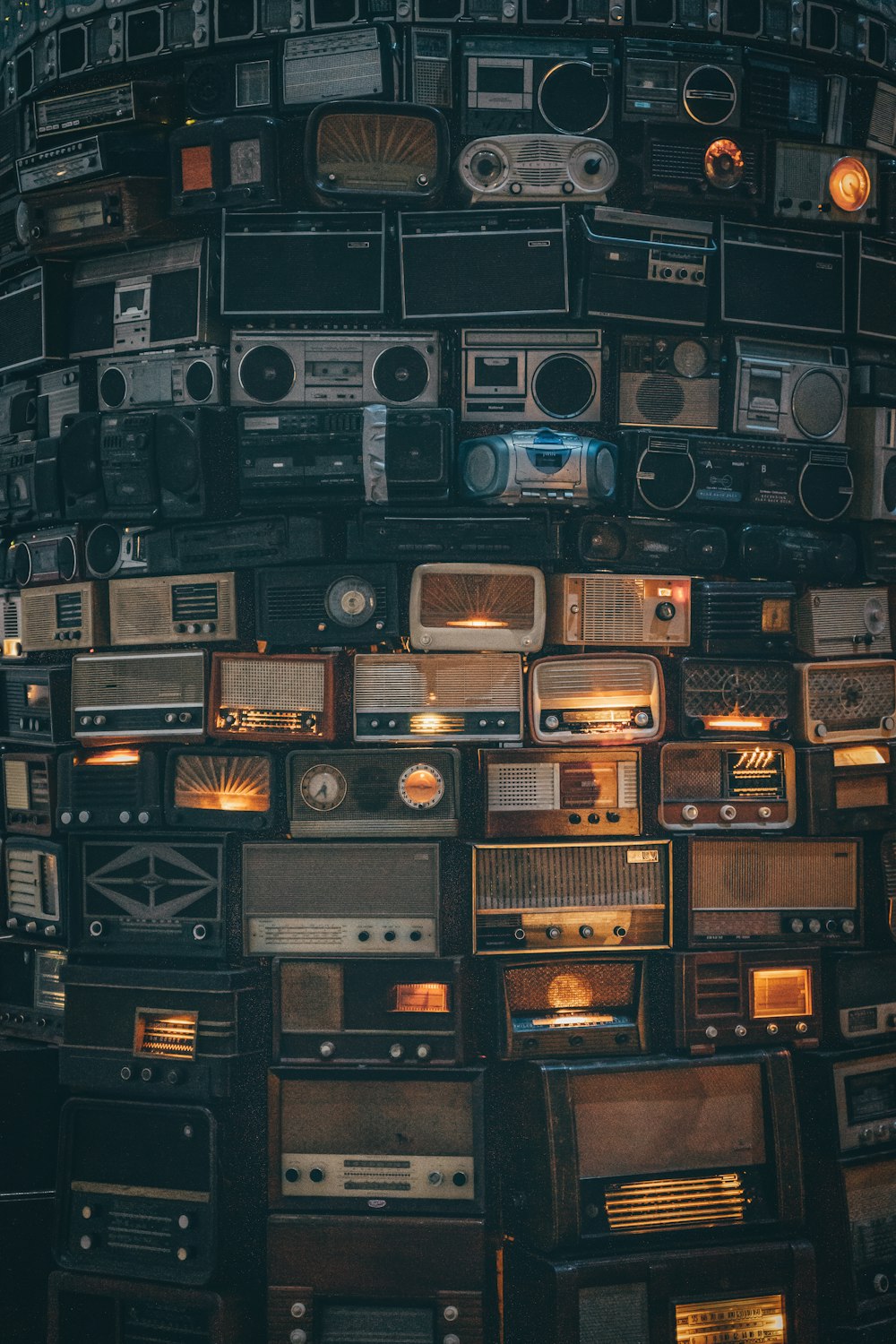 a large amount of old radio's stacked on top of each other