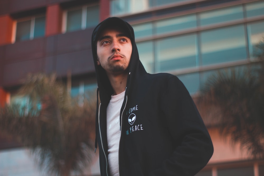 a man in a hoodie standing in front of a building