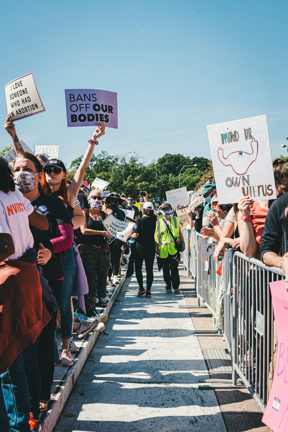 a group of people holding signs and standing on a sidewalk