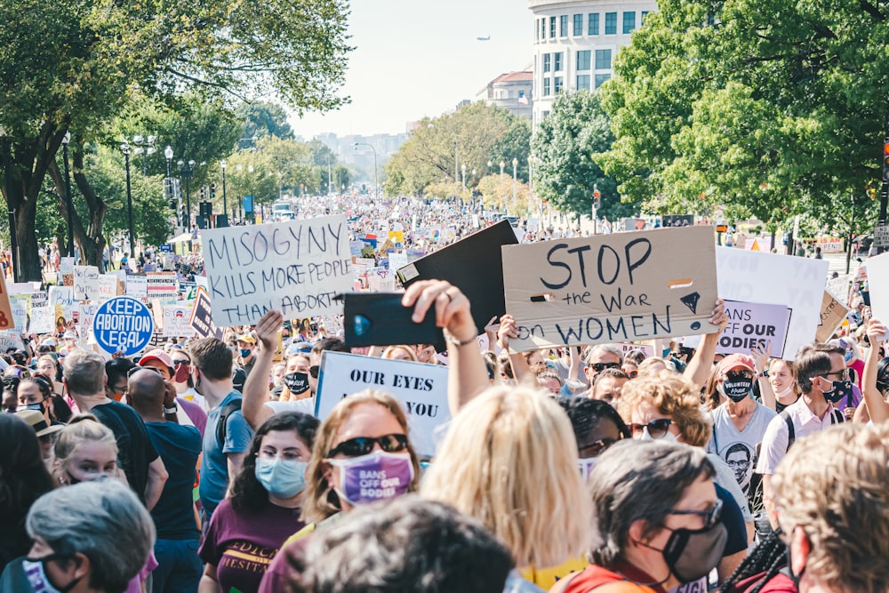 a crowd of people holding signs and wearing face masks