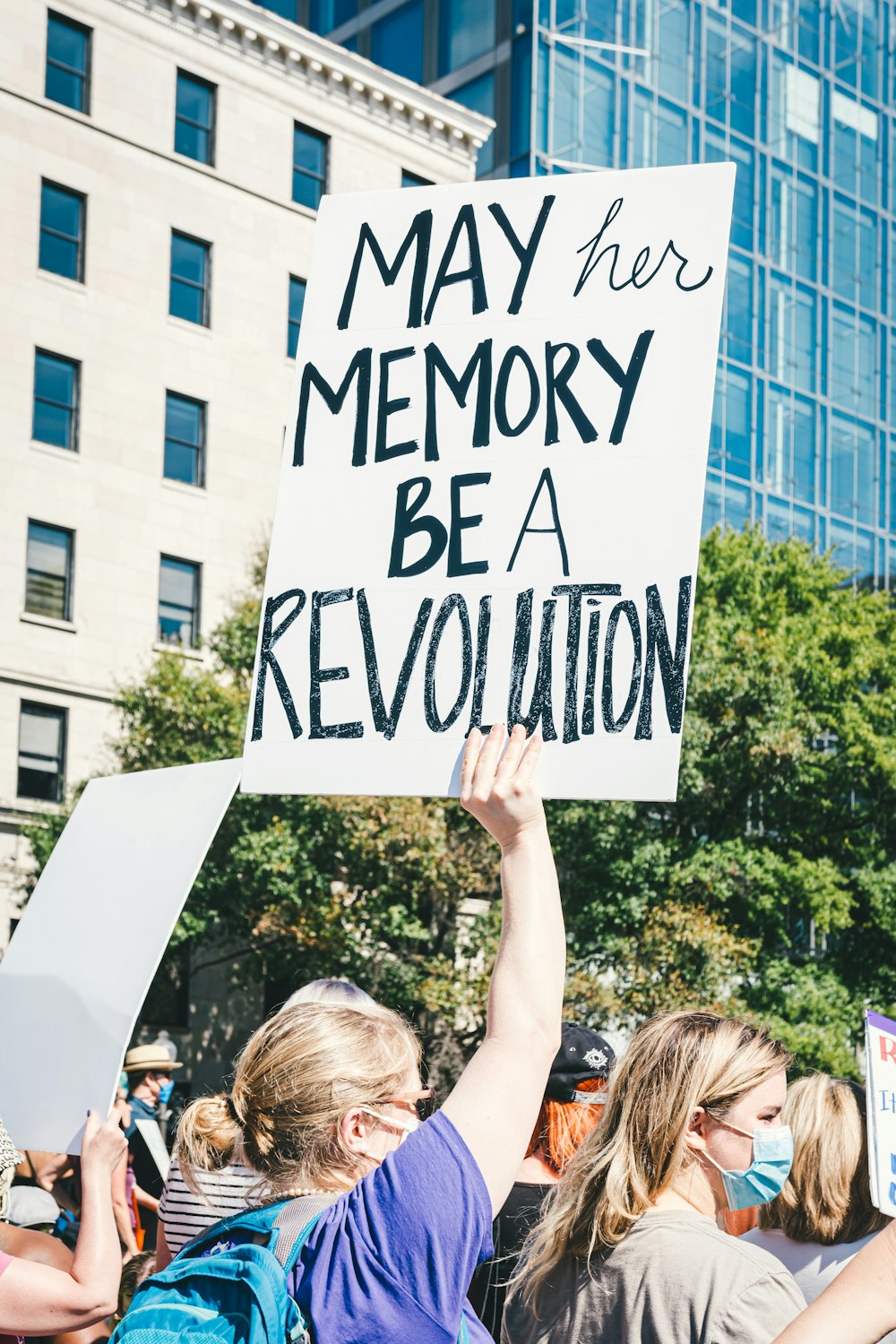 a woman holding a sign that says may her memory be a revolution