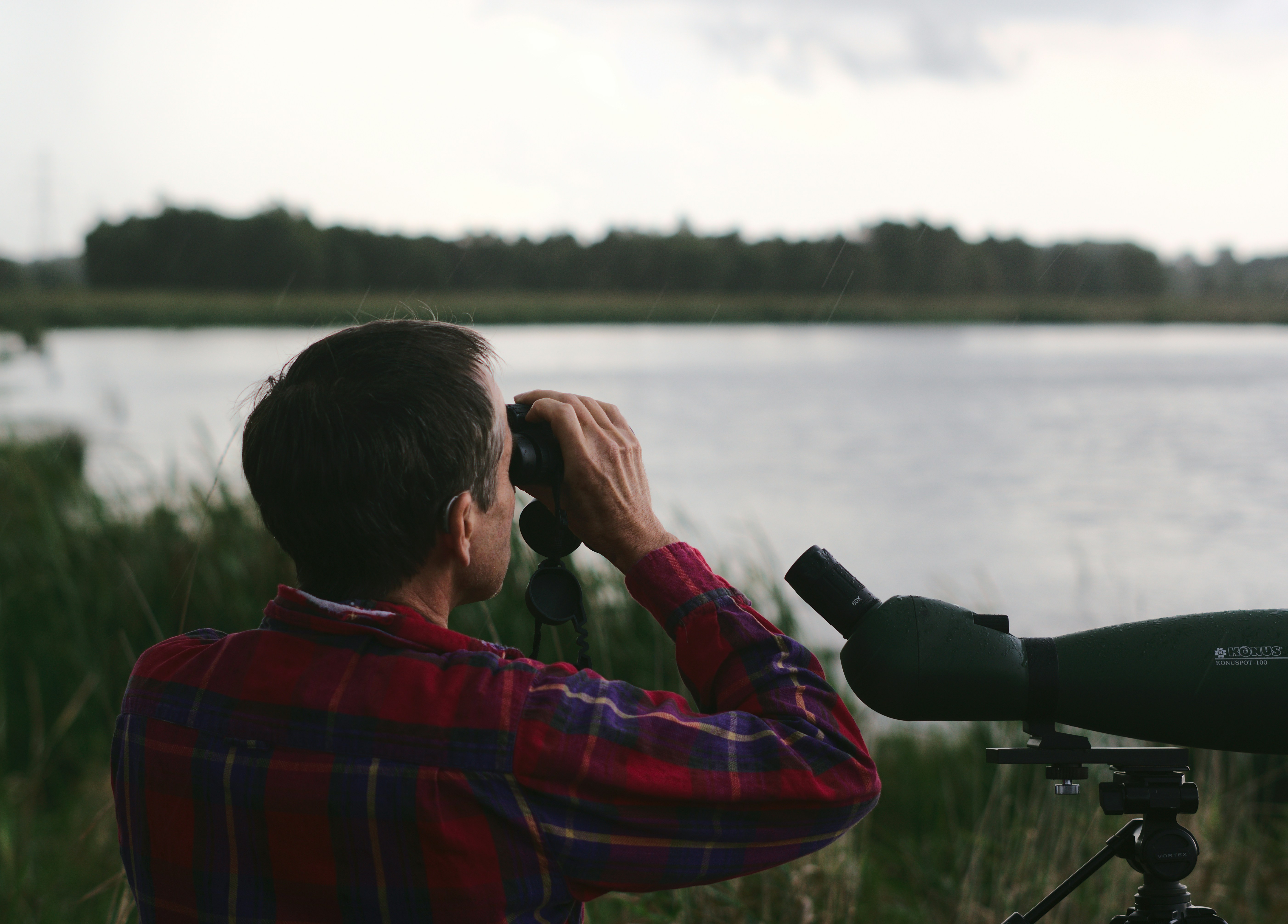 A man peers through a telescope at a lake
