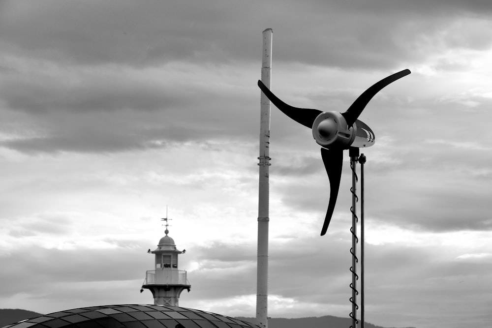 Una foto en blanco y negro de una turbina eólica y un faro