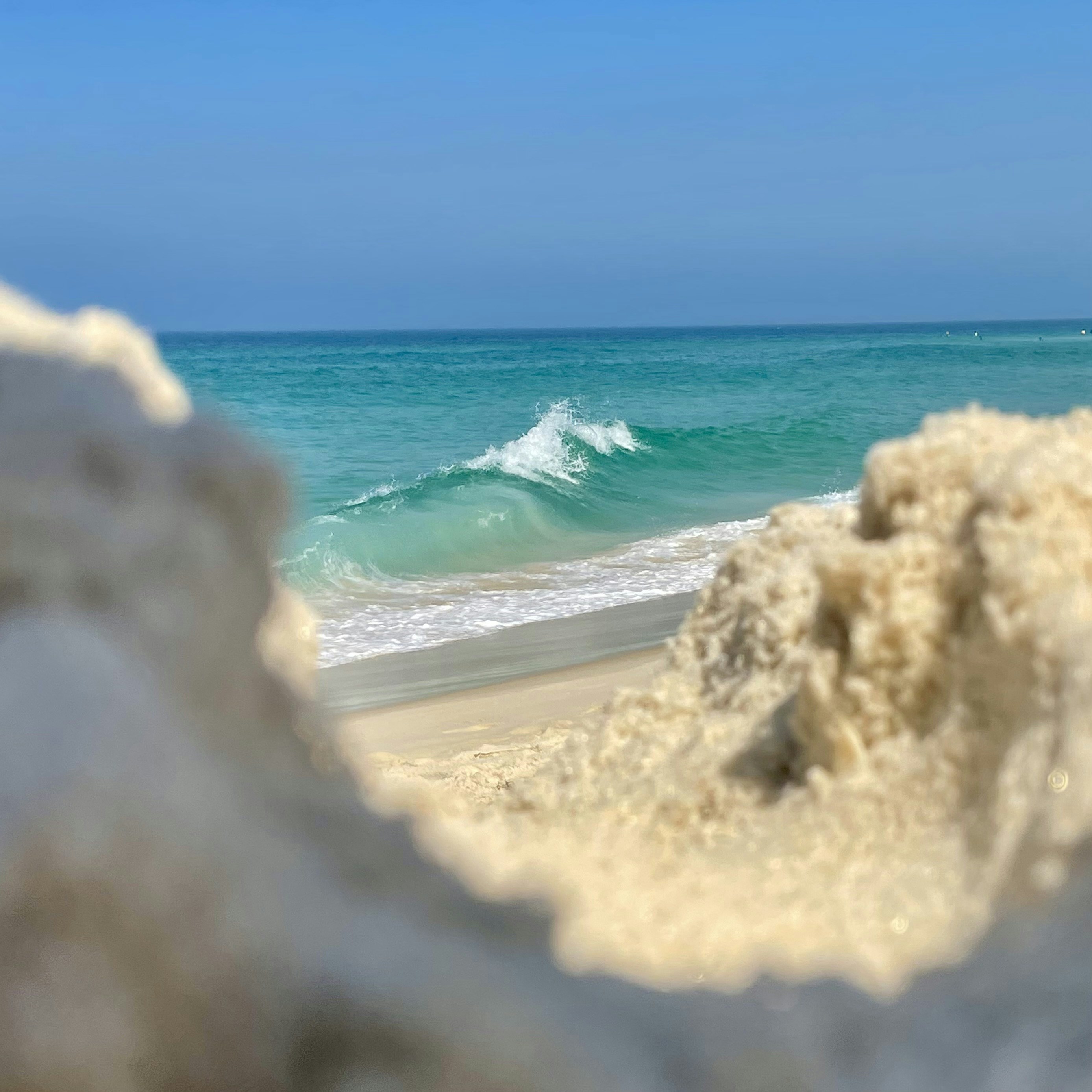 a view of the ocean from behind a rock