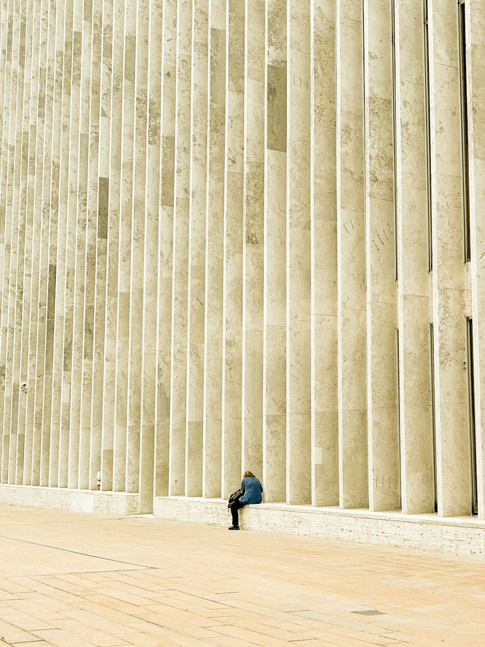 a person sitting on the ground in front of a building