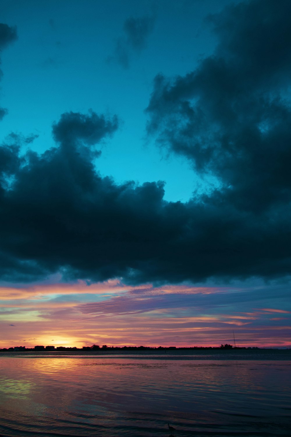 a boat sitting on top of a body of water under a cloudy sky