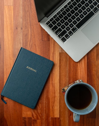 a laptop computer sitting on top of a wooden floor next to a cup of coffee