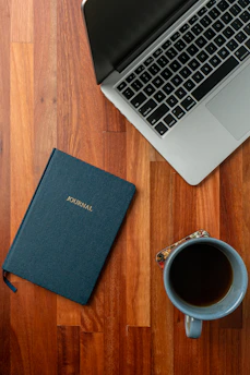 A cozy desk with a journal, coffee cup, and a laptop open to a blog post.