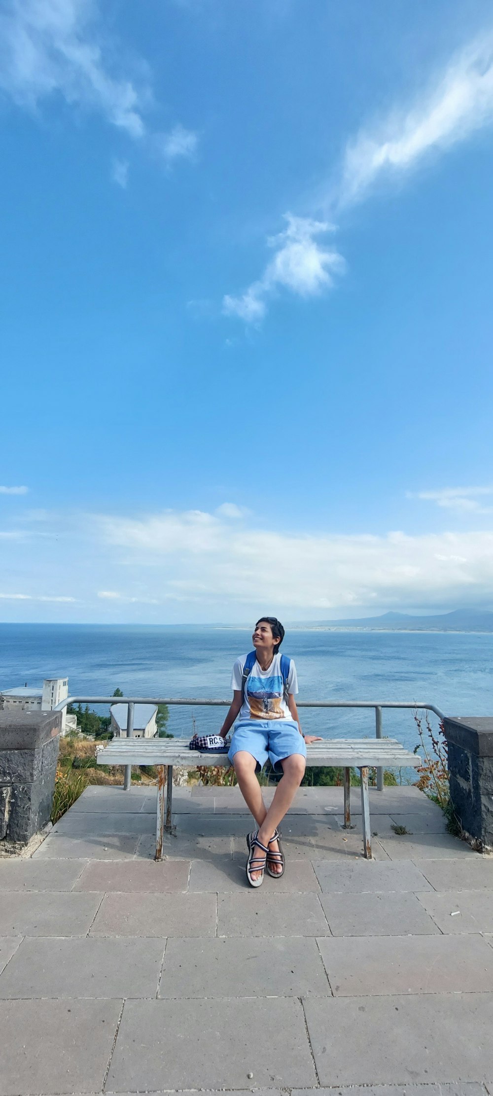 a woman sitting on a bench in front of the ocean