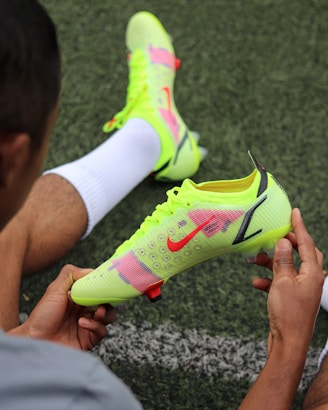 a man holding a pair of neon green shoes