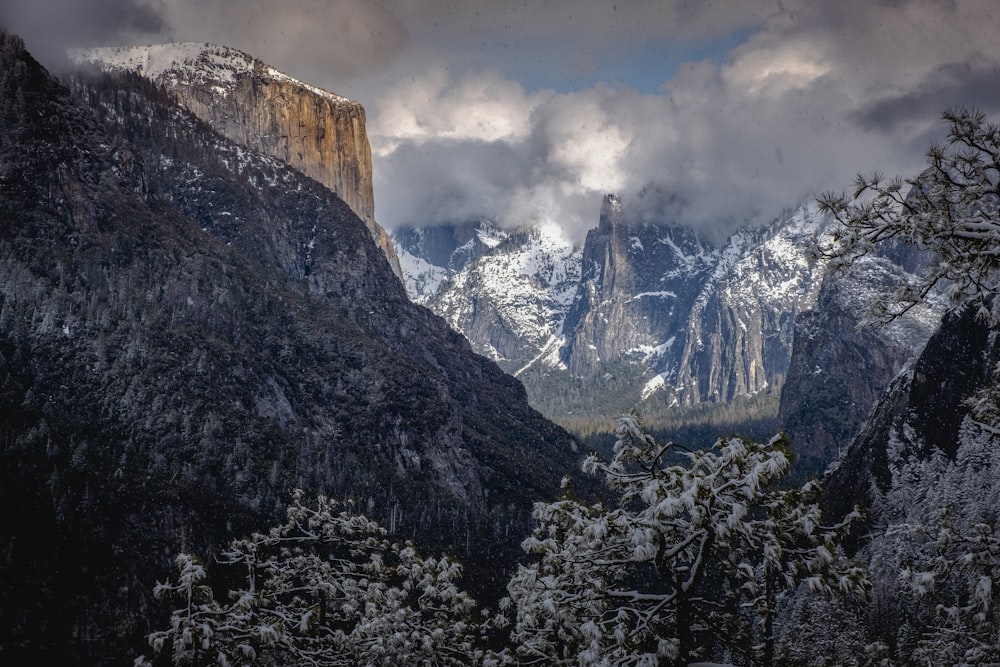 a mountain range covered in snow under a cloudy sky