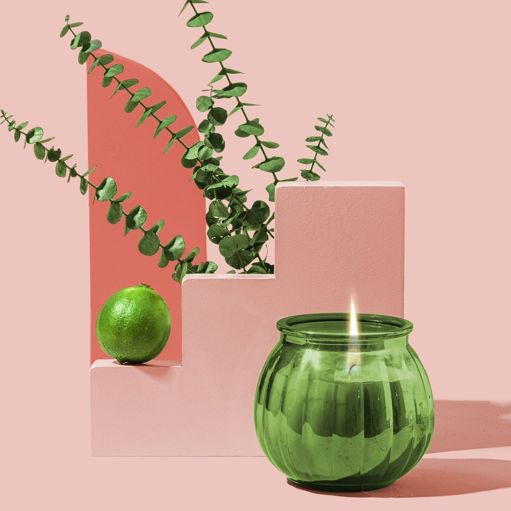 a green candle sitting next to a green plant